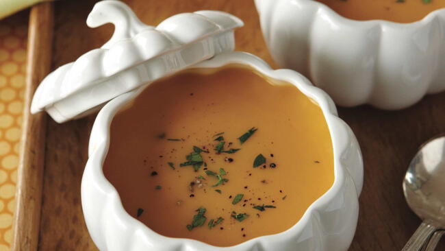 butternut squash soup in a white pumpkin ceramic cocquette with parsley and black pepper garnish