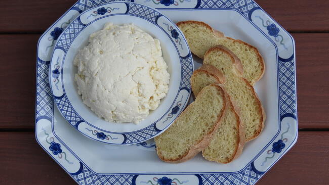 Bowl of cheese next to a plate of bread