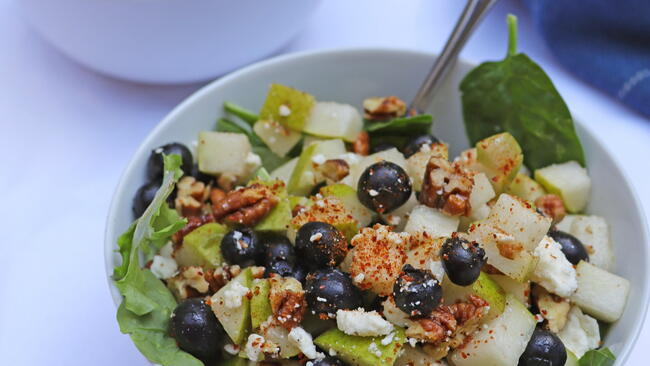 Pear salad in a bowl with spinach and blue berries