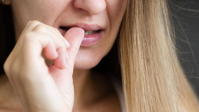 blonde woman biting her thumb nails, nail biter