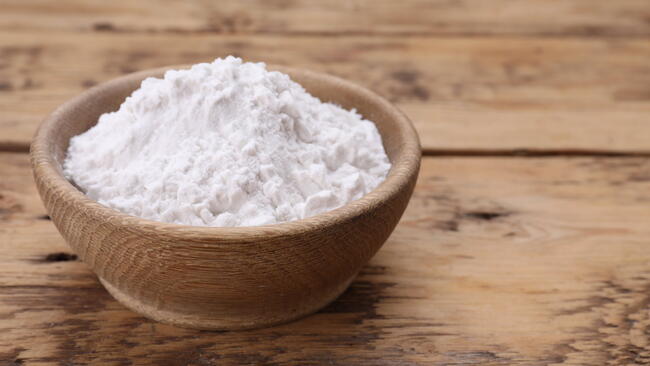 Bowl of natural starch on wooden table, closeup