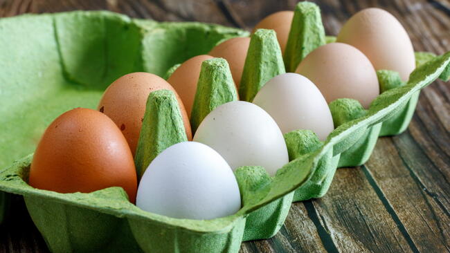 A green carton filled with ten multi-colored eggs