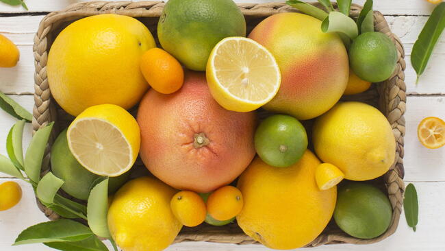 Top-down photograph of a basket filled with lemons, limes, and grapefruit