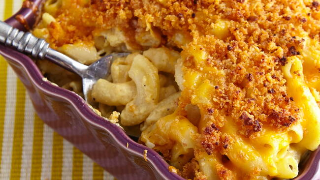 Close up photograph of mac and cheese topped with breadcrumbs in a purple dish 