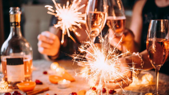 Friends celebrating Christmas or New Year eve party with Bengal lights and rose champagne.