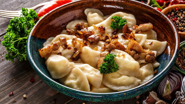 Pierogi or pyrohy, varenyky, vareniki, dumplings served with caramelized salted onion in bowl on wooden table - traditional Ukrainian food