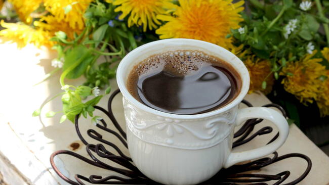 Cup of coffee on a wooden table. with dandelions