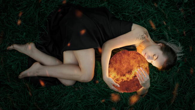 A woman in a black dress embraces the planet Venus