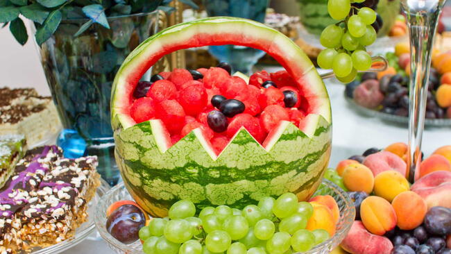 Watermelon basket. Decorative artistic fruit carving. Wedding catering company table. Colorful vitamin background. Various selection of fruits on banquet reception.