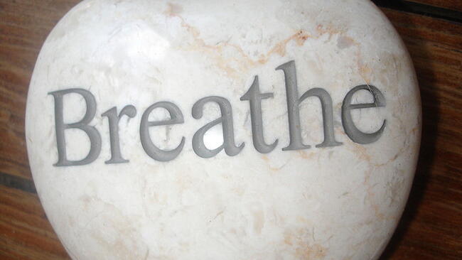 white stone heart engraved with the word "breathe"