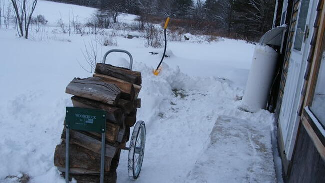 a "woodchuck" firewood cart, on a snowy path beside a door