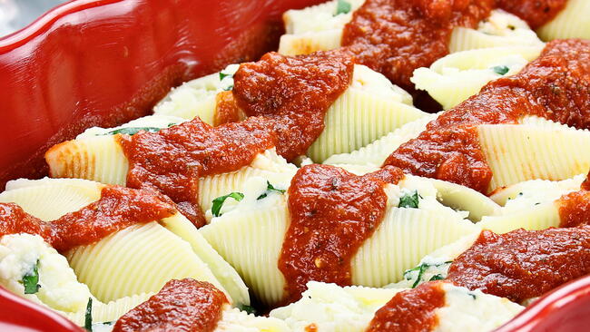 herb stuffed pasta shells with sauce in a red pan