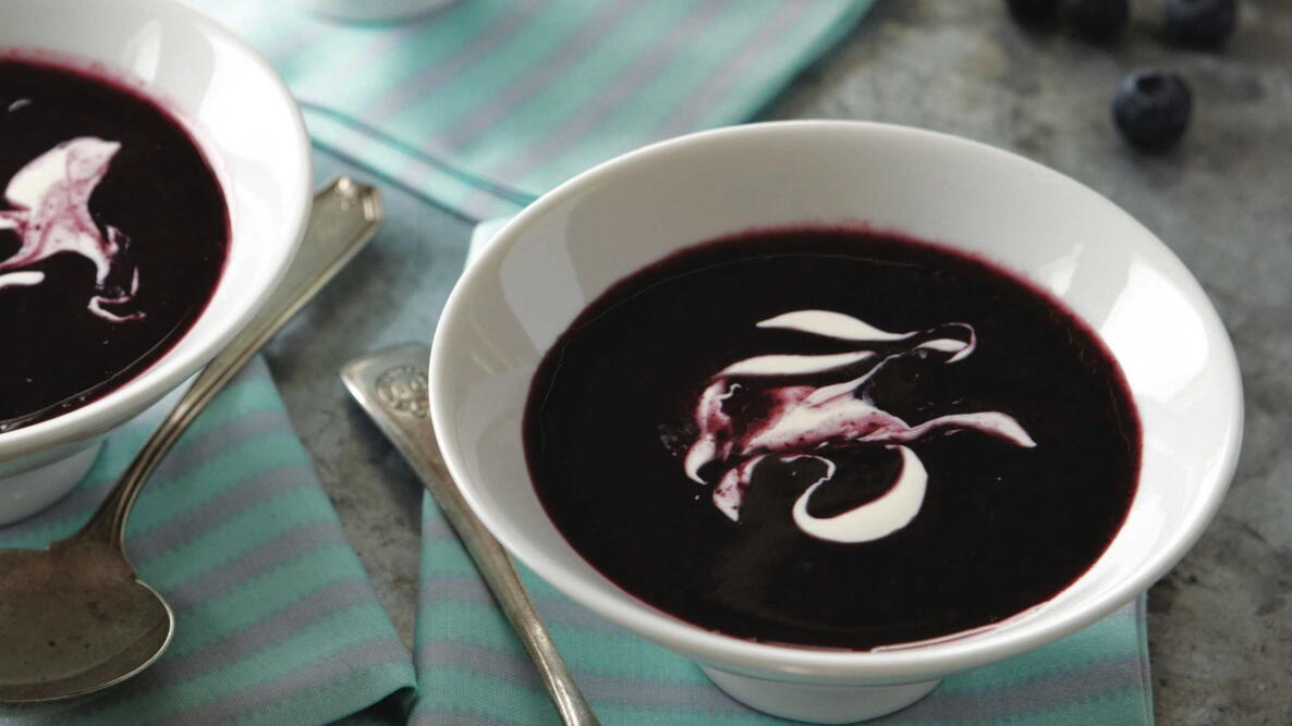 chilled blueberry soup in white bowls with yogurt on top