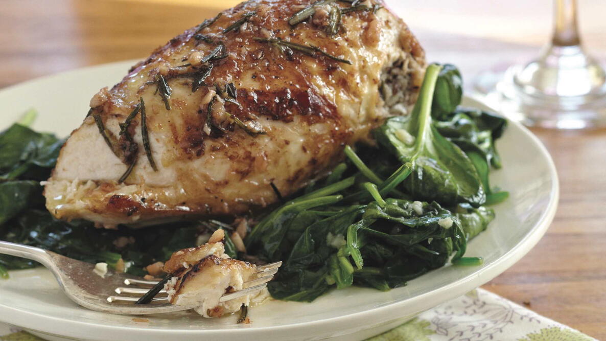rosemary chicken with spinach on a plate for dinner with a fork