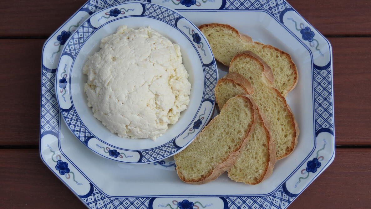Bowl of cheese next to a plate of bread