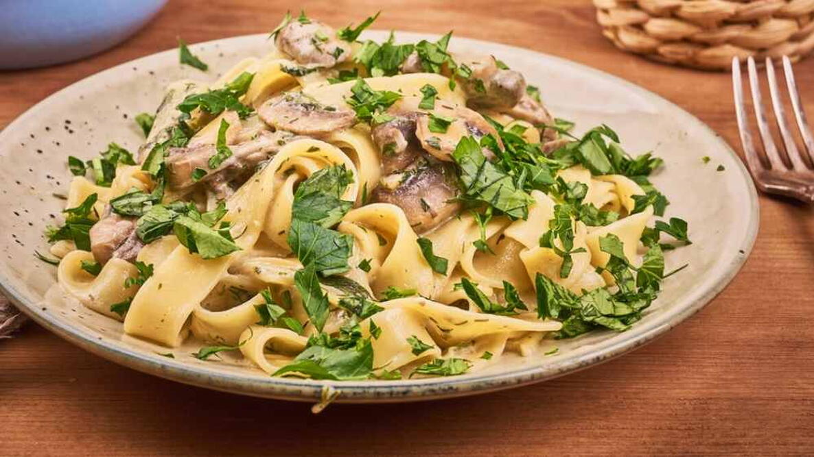 Fettuccine with mushroom sauce and fresh parsley in a plate, close-up - classic italian pasta
