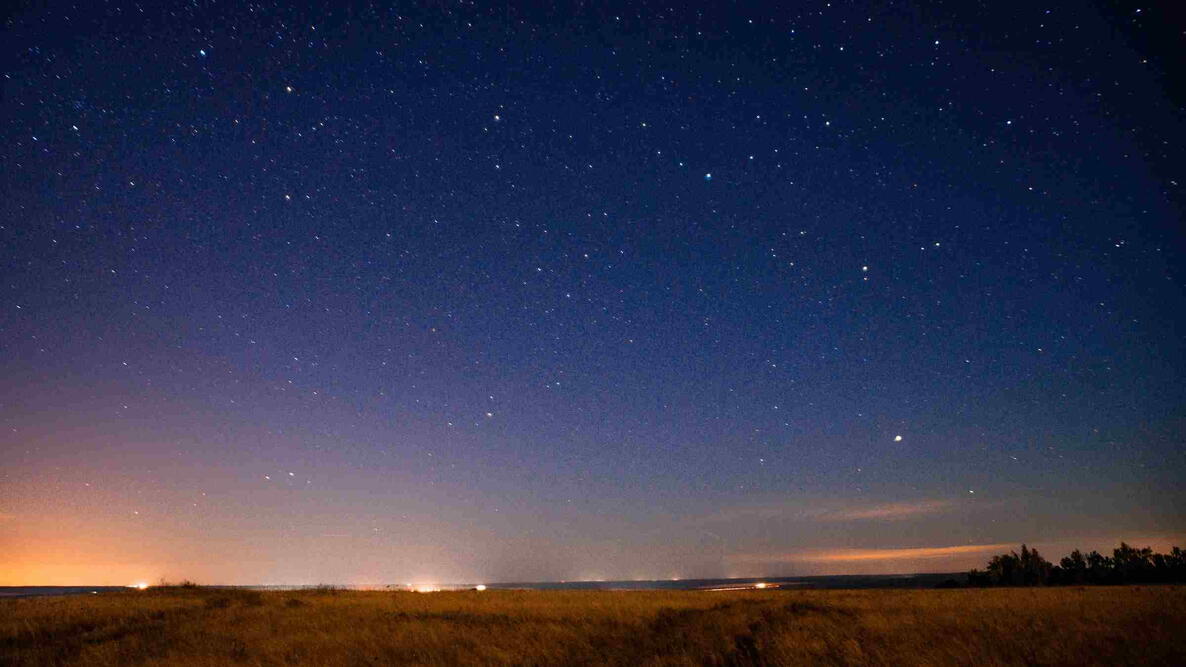 Stars visible in a deep blue twilight sky above a flat horizon.