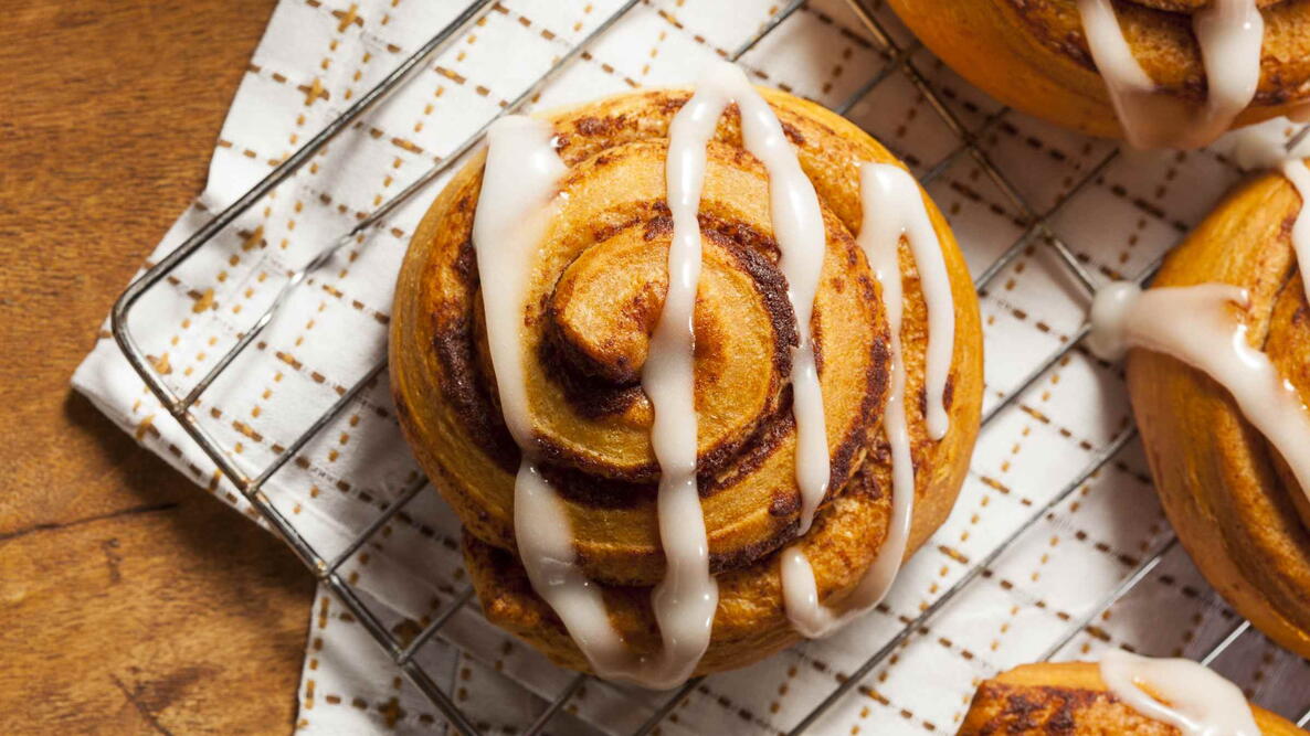 big oversized cinnamon roll with frosting on it cooling on a rock with a towel underneath it