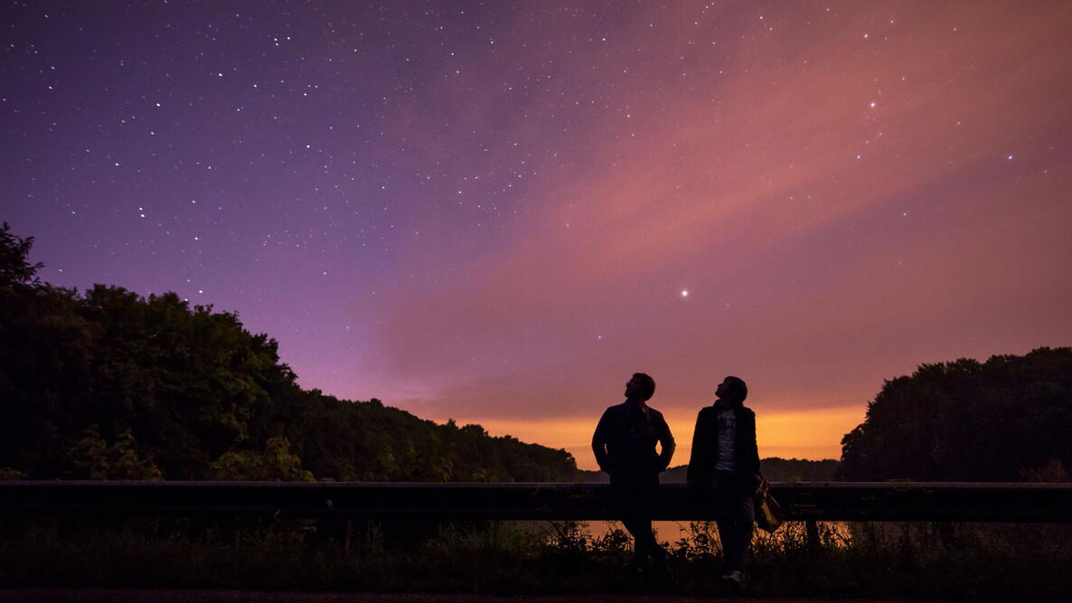 Two people looking at the stars, backlight, the starry sky through the clouds bump highway