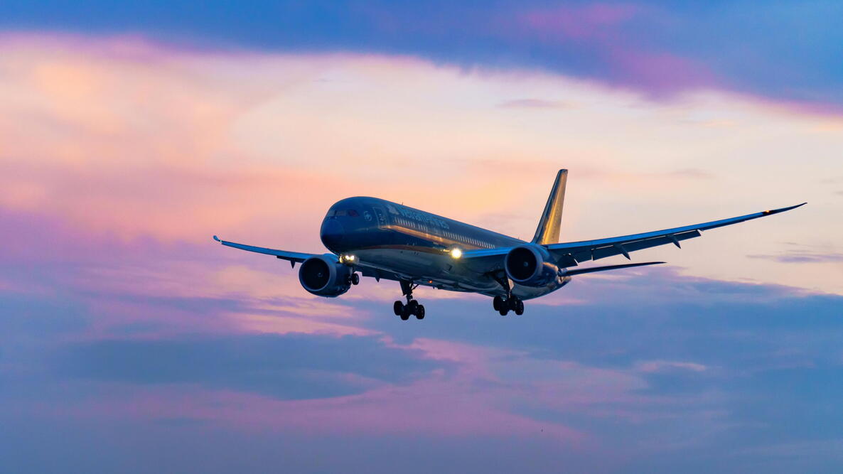 airplane flying in a multicolored sunset sky