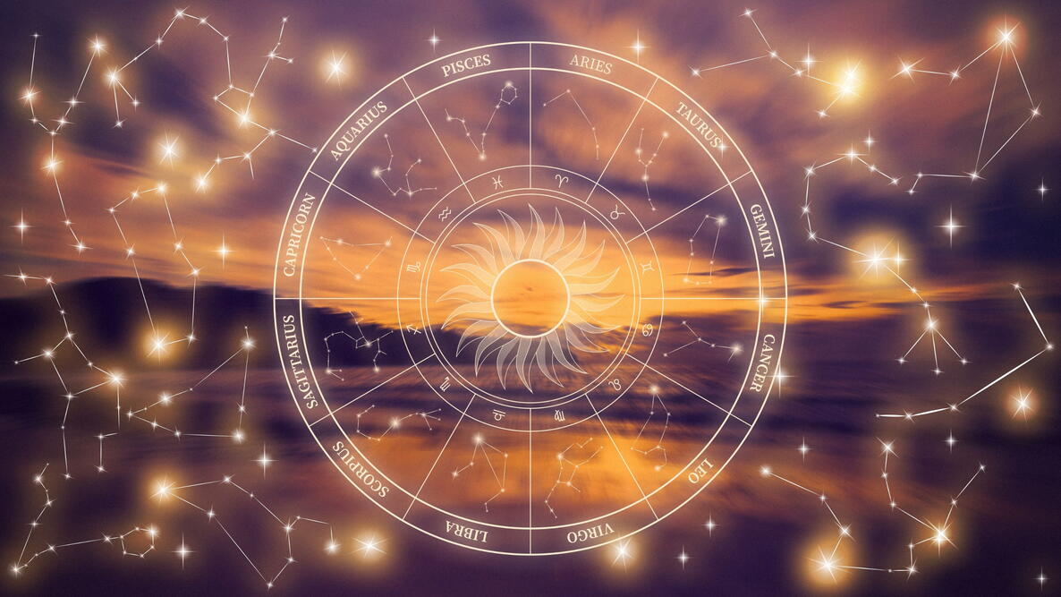 Astrology zodiac signs with constellations over a sunset sky by the ocean