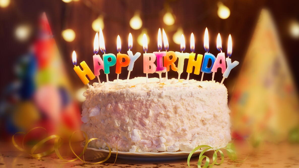 white birthday cake with happy birthday candles