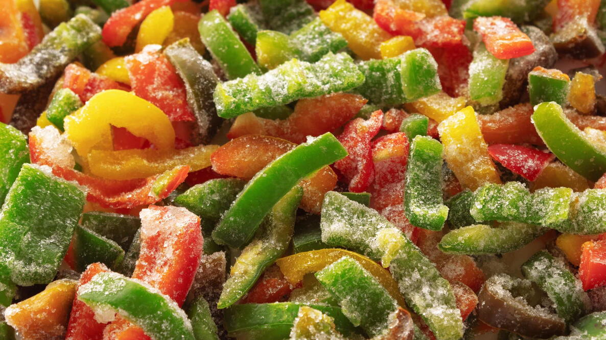 Frozen sliced bell pepper covered with ice. Frozen vegetables background. Selective focus.