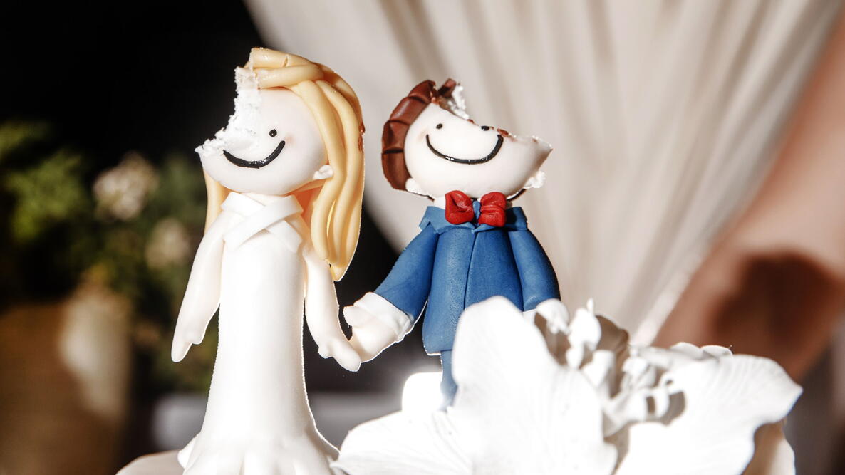  figurines of the bride and groom on the wedding cake with heads bitten off