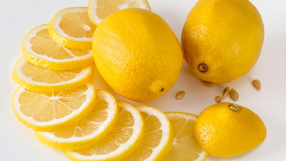 Lemons, lemon slices, and lemon seeds on a white table