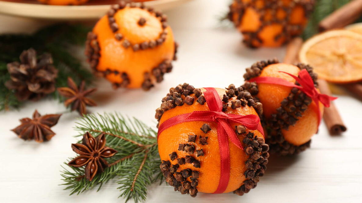 Pomander balls made of fresh tangerines with cloves on white wooden table. Christmas atmosphere