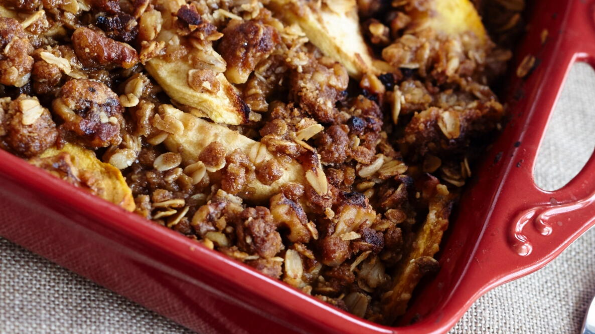Close-up of peach crisp in a red baking pan 