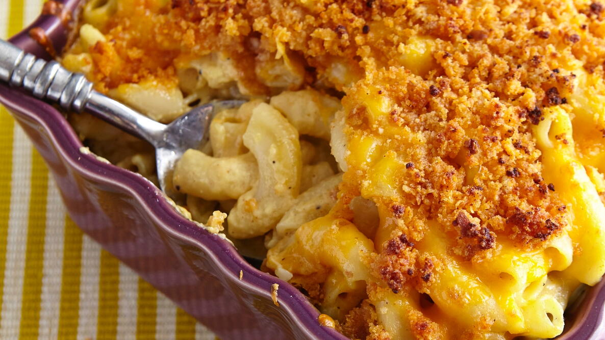 Close up photograph of mac and cheese topped with breadcrumbs in a purple dish 
