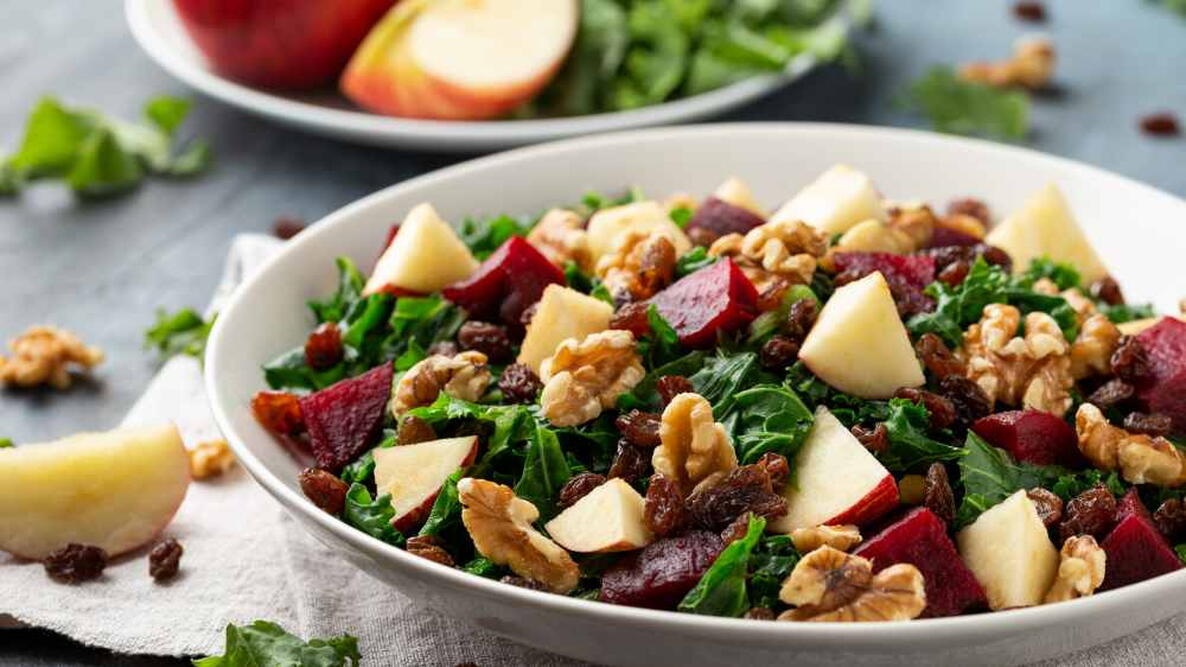 salad with apple, beetroot, walnut and raisins in white plate. Healthy food