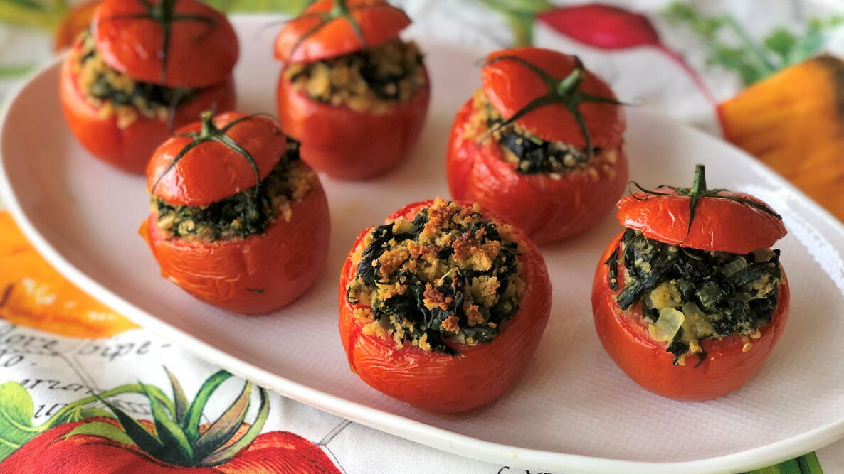 Fresh tomatoes stuffed with spinach and onions on a white plate