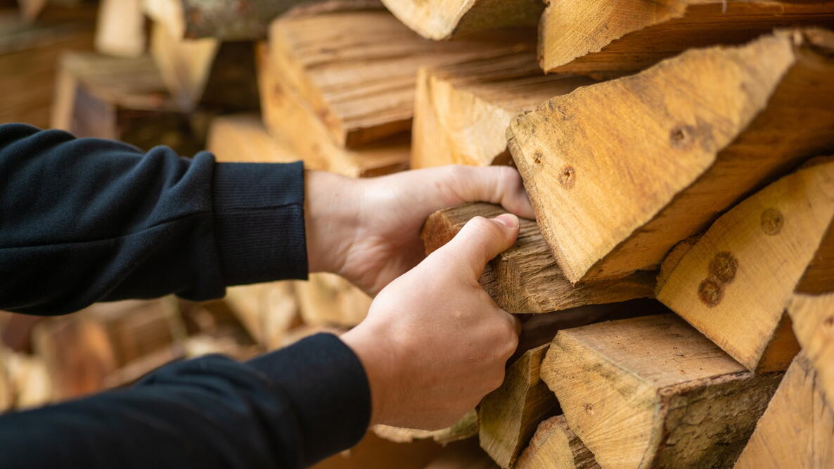 Heating season. Firewood.hands pulling a log from a woodshed. Male hands pulling a log from a woodshed.Heating season. Firewood and mens hands close-up.