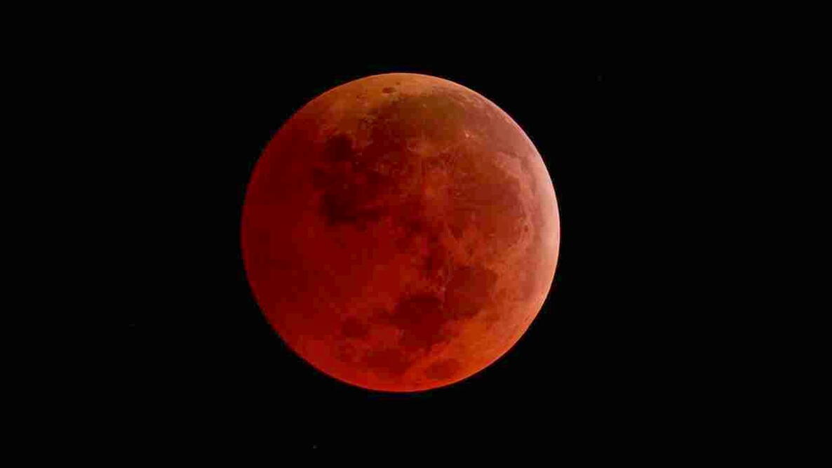 The Moon appearing red during a total lunar eclipse against a dark night sky.