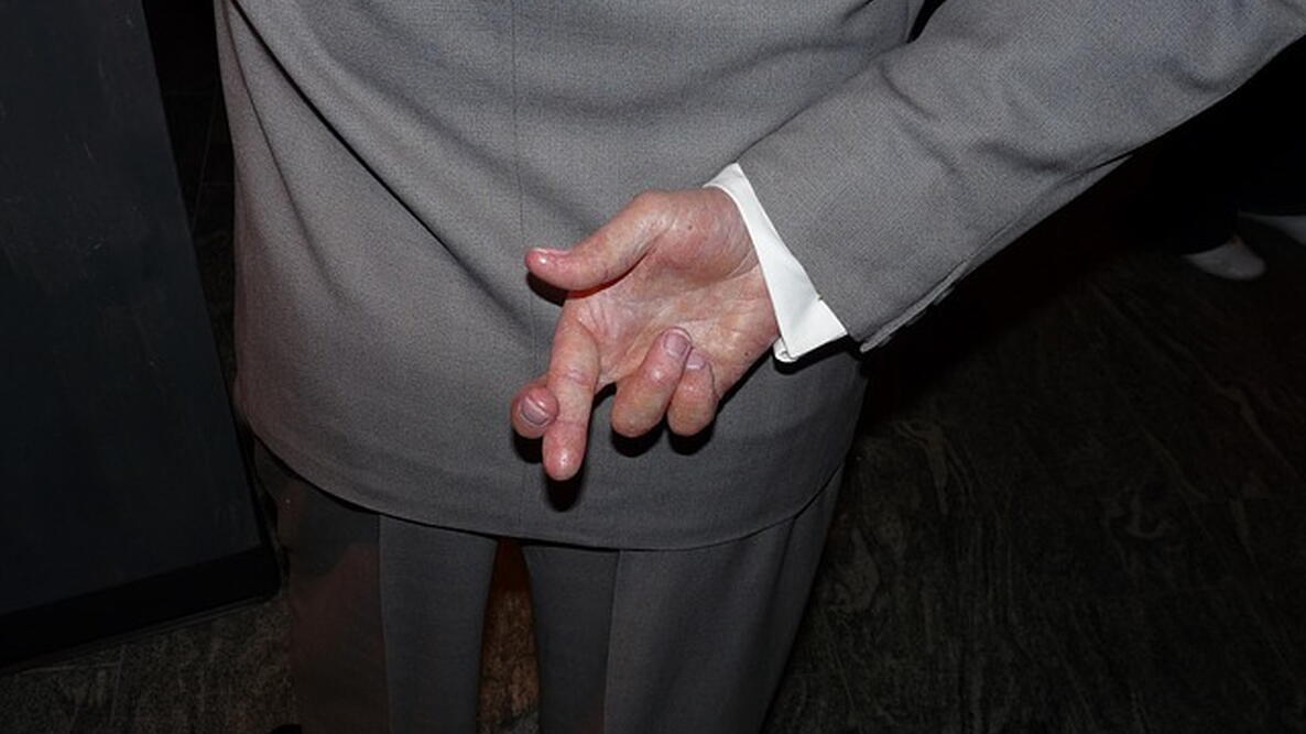 fingers crossed behind a man's back
