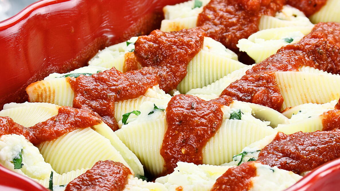 herb stuffed pasta shells with sauce in a red pan