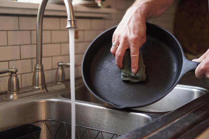 scrubbing a cast iron pan at the sink