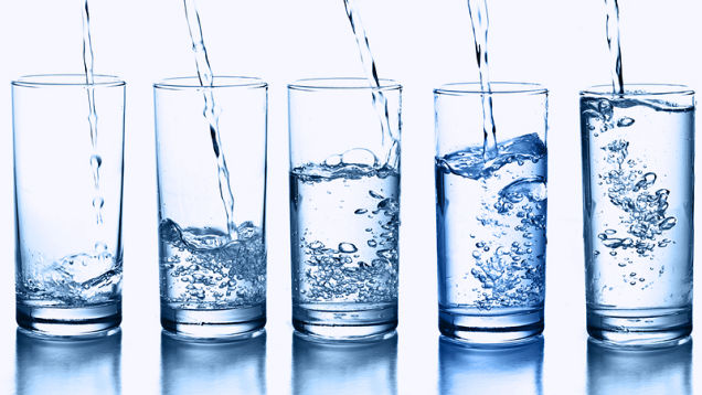 five water glasses with water being poured in
