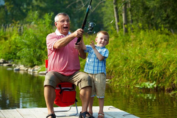 boy fishing with his grandfather on a dock