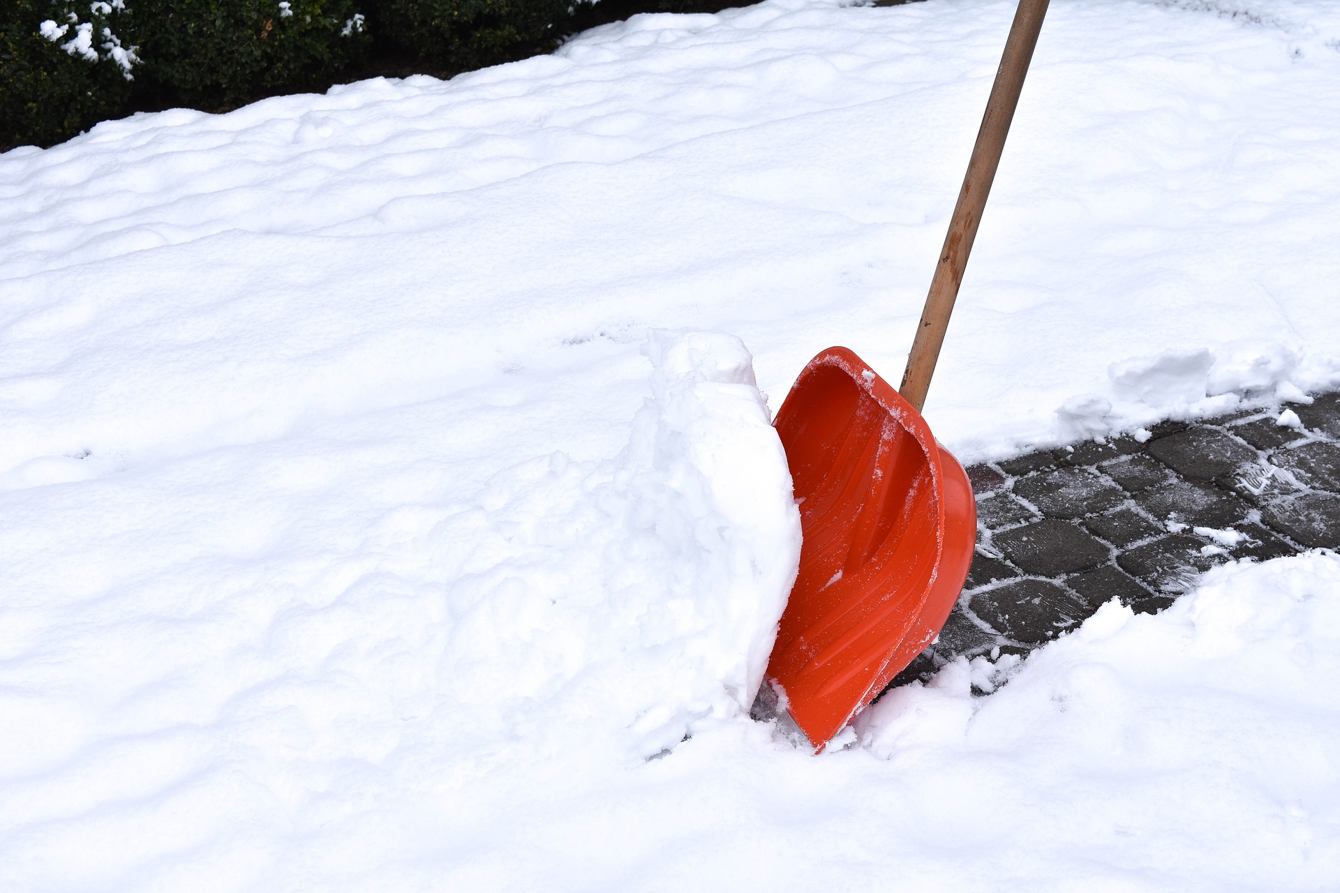 orange snow shovel in the snow making a path