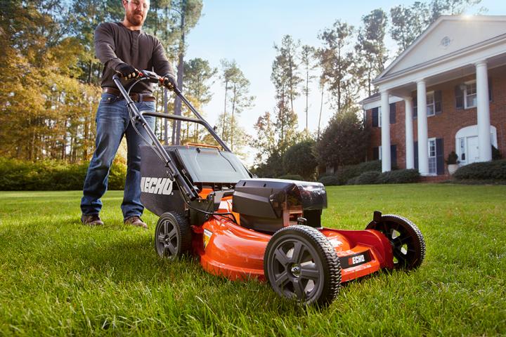 Image: Cutting the grass with an electric cordless lawn mower.